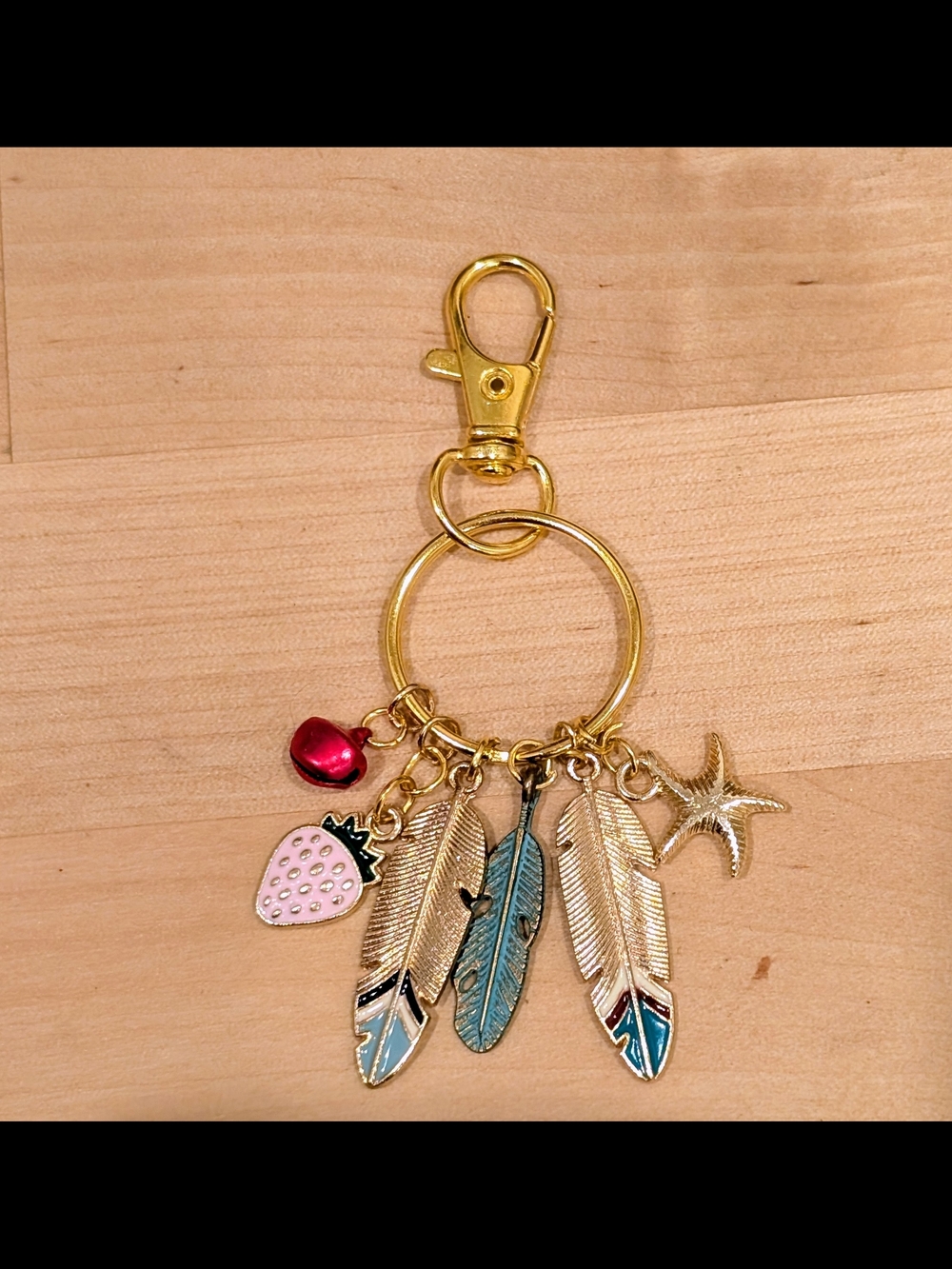 Gold Tone Feather Charm Keyring with Pink Strawberry and Jingle Bell Accents